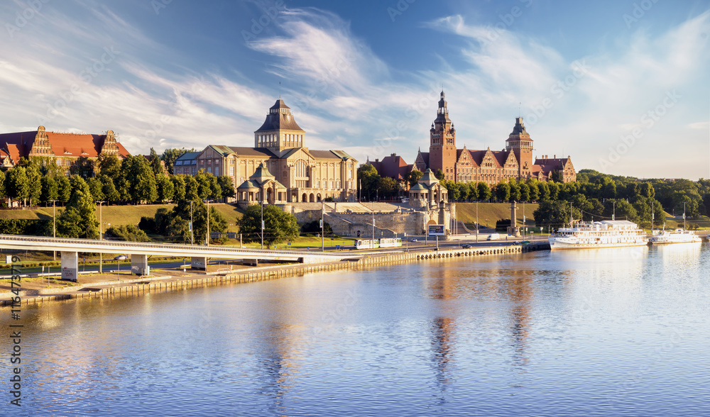 Wały Chrobrego w Szczecinie, widok na terasy Hakena, rzeka Odra, zabytkowa architektura i budynki, intensywne kolory nieba oraz wody, spokojny i elegancki klimat, letni dzień.