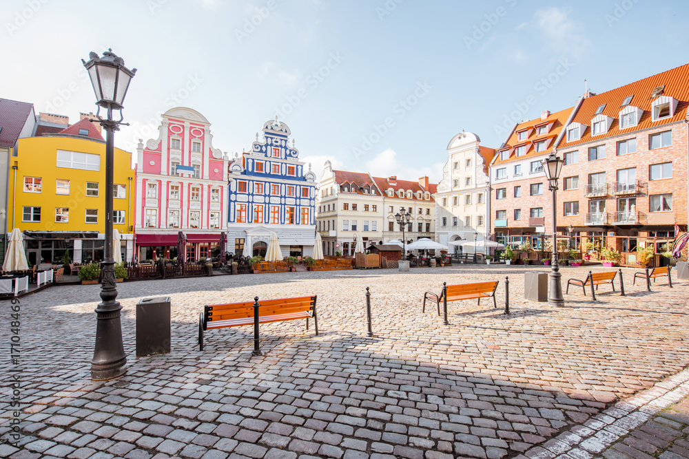 Malowniczy rynek w Szczecinie - zabytkowe kamienice w żywych kolorach różu, błękitu i żółci okalają historyczny plac wyłożony oryginalnym brukiem, klasyczne latarnie i drewniane ławki dodają romantycznego charakteru