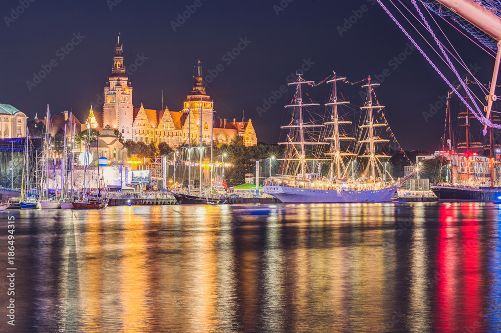 Szczecińskie dźwigi portowe i diabelski młyn podczas festiwalu światła - hipnotyzujący spektakl neonowych barw odbijających się w wodzie, tworzący magiczną atmosferę nocnego karnawału w stylu cyberpunk