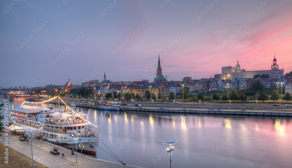 Panorama nadmorskiego Szczecina o zmierzchu - historyczne nabrzeże skąpane w różowej poświacie, z eleganckimi statkami pasażerskimi na pierwszym planie i majestatycznymi wieżami kościołów oraz Zamku Książąt Pomorskich na horyzoncie