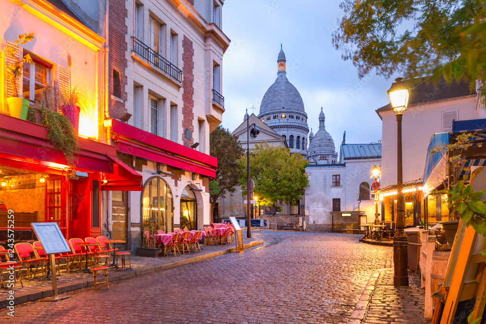 Uliczka Montmartre z widokiem na bazylikę Sacré-Cœur o zmierzchu w Paryżu