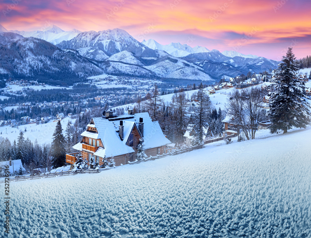 Obraz przedstawiający zimowy krajobraz Zakopanego o zmierzchu z widokiem na ośnieżoną chatę i Tatry w tle