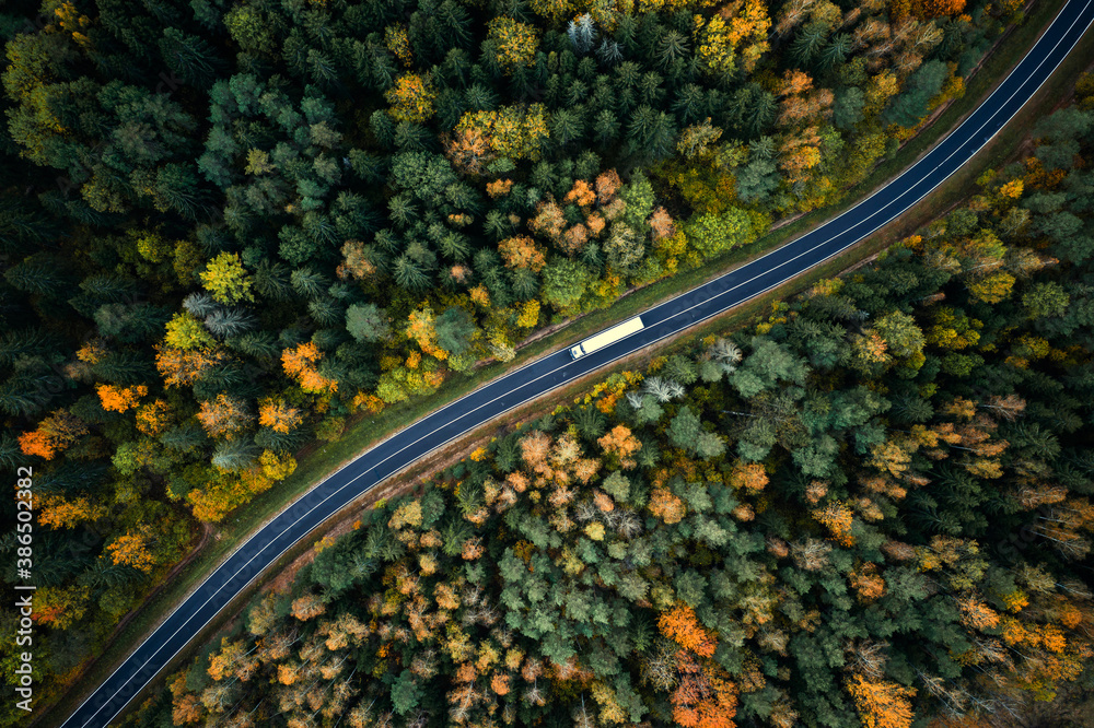 Aerial view of a twisting road through a colorful autumn forest