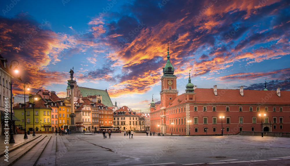 Plac Zamkowy w Warszawie podczas spektakularnego zachodu słońca - płonące pomarańczowo-różowe chmury nad zabytkowym zespołem kamieniczek w ciepłych barwach, z dominującym Zamkiem Królewskim i kultową Kolumną Zygmunta