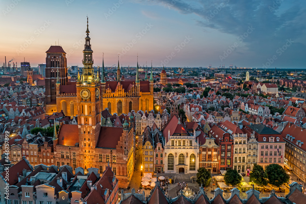 Panoramiczne ujęcie z lotu ptaka na zabytkowe centrum Gdańska z ratuszem i kamienicami w ciepłym świetle wieczornym; fotografia miejska w stylu vintage.