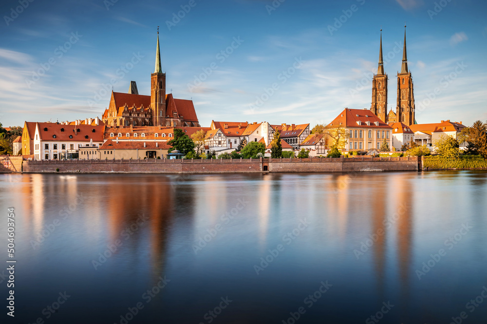 Panorama Wrocławia nad Odrą z widokiem na Katedrę Świętego Jana Chrzciciela w ciepłym, wieczornym świetle.