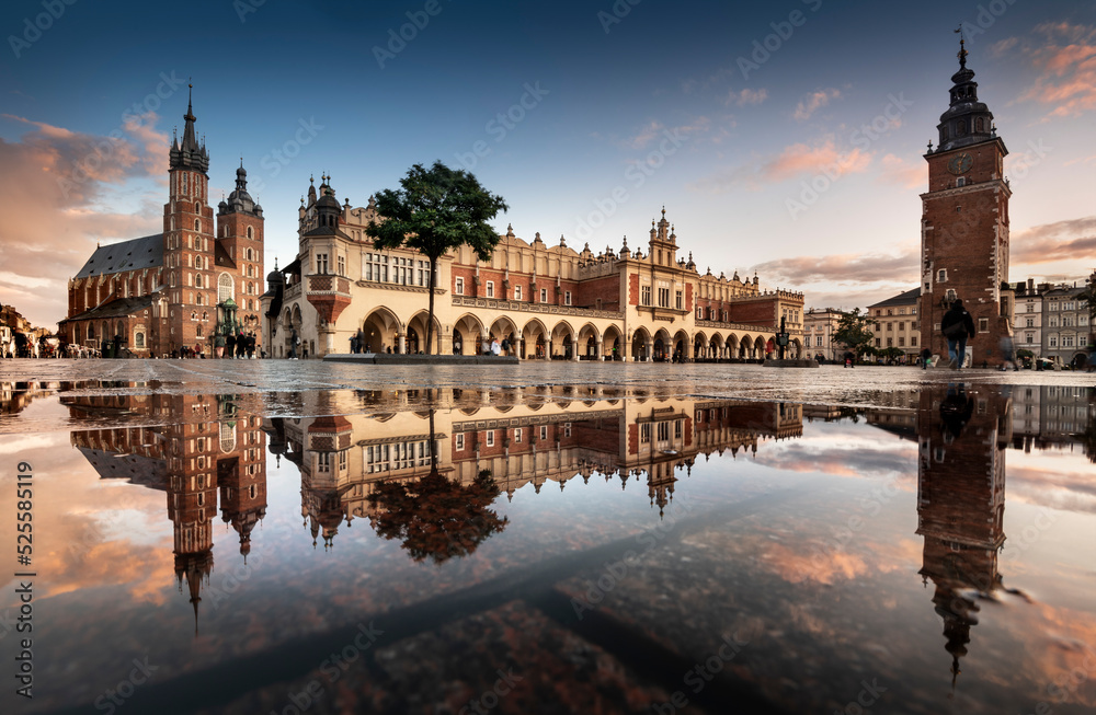 Obraz na płótnie przedstawiający Sukiennice i Kościół Mariacki w Krakowie, z odbiciem w kałuży na Rynku Głównym, idealny do klasycznych i nowoczesnych wnętrz.